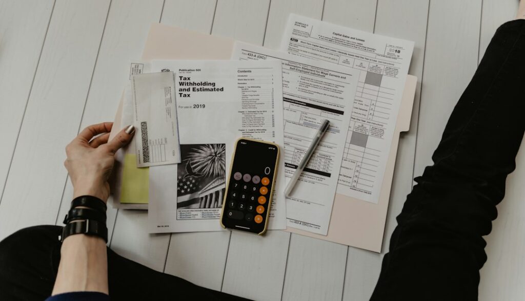 Hand mit Rechnungsunterlagen neben Taschenrechner und Stift bei der Liquiditätsplanung